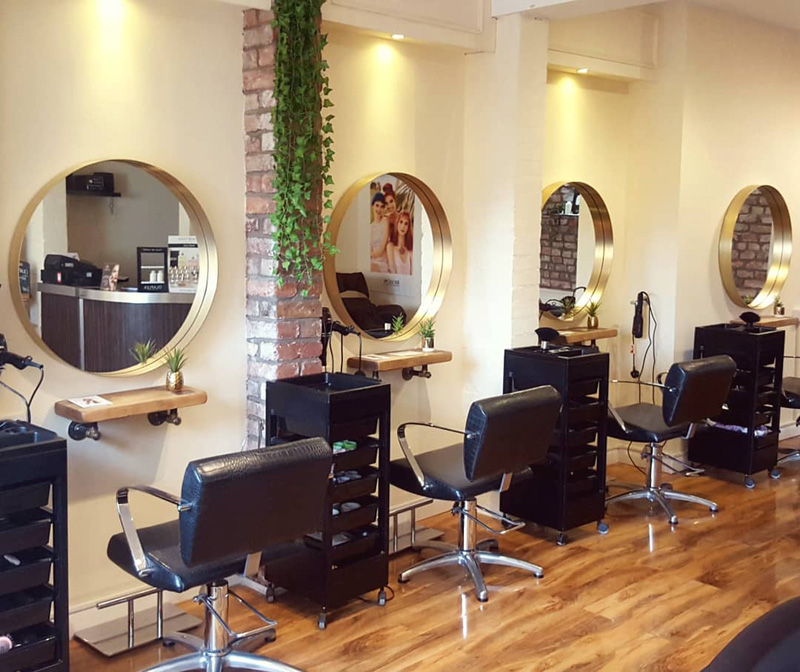 industrial style hair salon with gold mirrors and black chairs