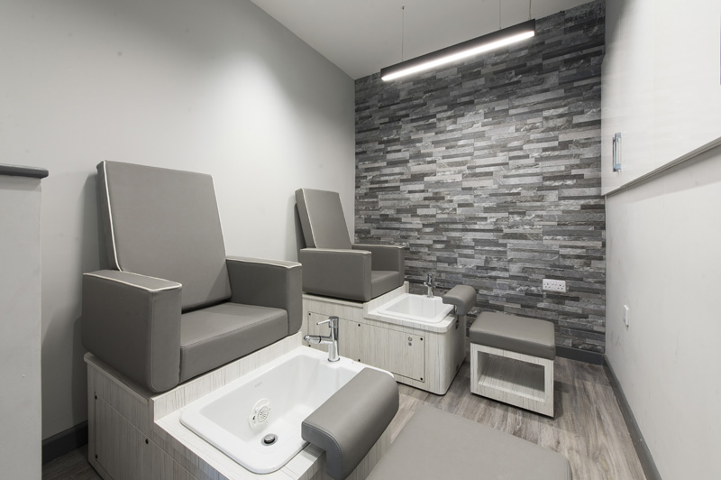 grey and white pedicure chairs with feet basin stone wall